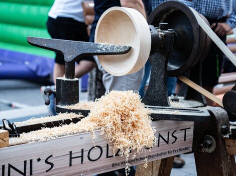 Eine Holzlathe wird verwendet, um eine Schüssel zu drechseln. Späne fallen von der Maschine auf den Boden.