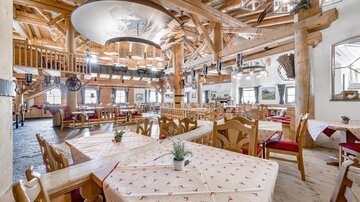 Ein einladendes Restaurant mit Holzdekor und gemütlichen Tischen. Große Fenster bieten viel Licht und einen Blick auf die gemütliche Atmosphäre.