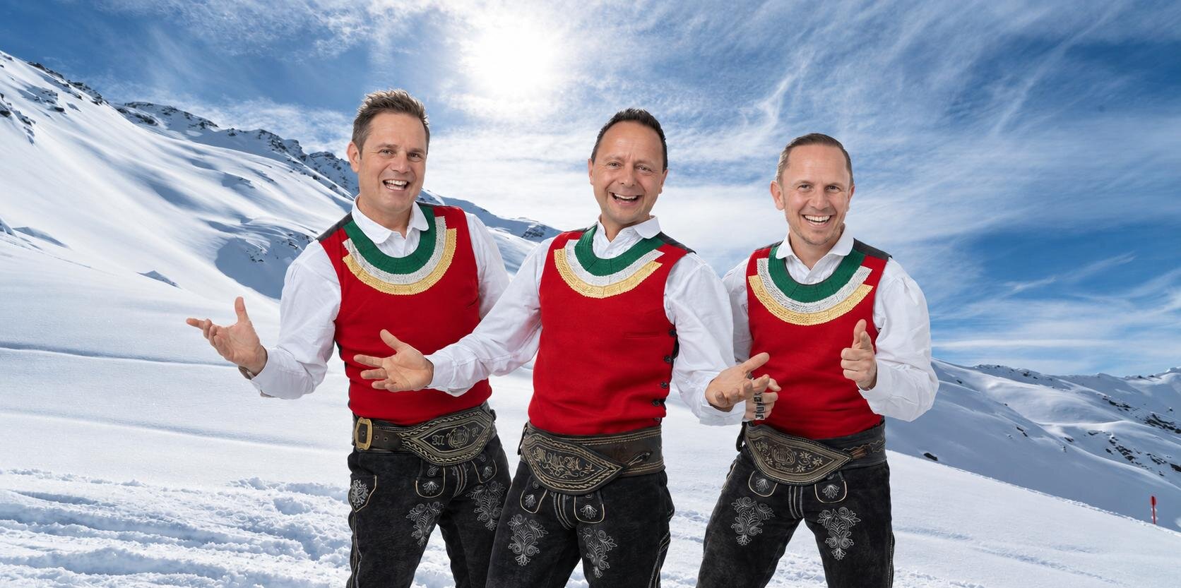 Ein Skifahrer fährt die Piste hinunter. Im Hintergrund sind schneebedeckte Berge und ein klarer Himmel zu sehen.