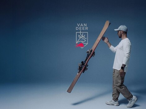 Ein Mann hält Skier in einer ruhigen, blauen Umgebung. Im Hintergrund steht ein Hinweis auf ein Pop-Up-Testzentrum in Ischgl vom 5. bis 8. Dezember 2025.