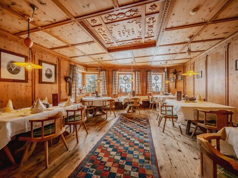 Ein gemütliches Restaurant mit Holzwänden und Tischen. Der Raum ist warm beleuchtet und hat ein einladendes Ambiente.