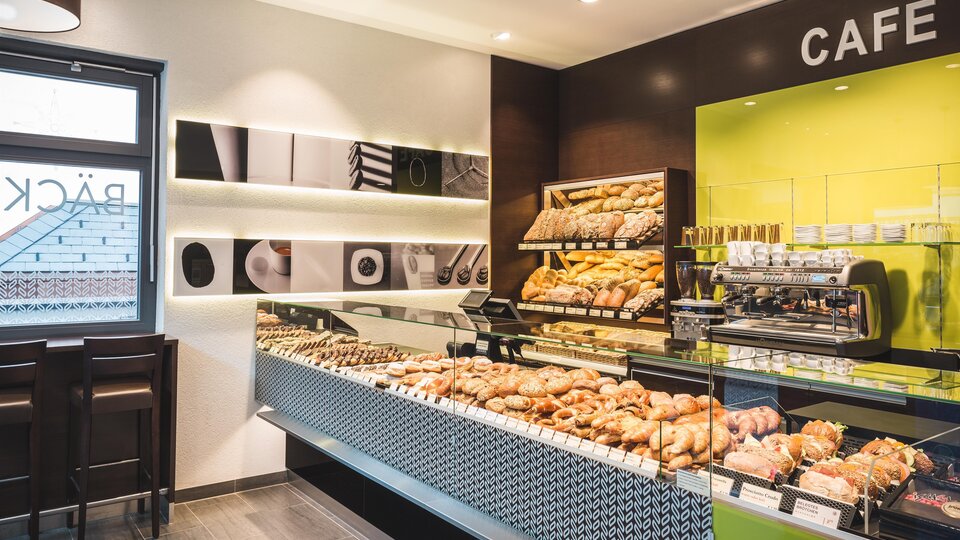 A modern café with a large selection of fresh baked goods. The bright colors and inviting atmosphere create a cozy environment.
