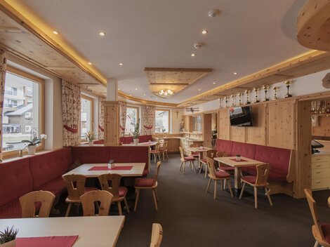 Ein gemütliches Restaurant mit Holzdekor und roten Polsterbänken. Es gibt Tische mit Platz für Gäste und große Fenster, die natürlichem Licht hereinzulassen.