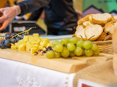 Ein schön gedeckter Tisch mit frischem Brot, Käse, Trauben und Nüssen. Die farbenfrohe Präsentation lädt zum Genießen ein.