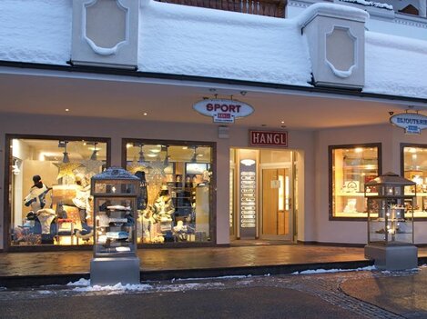 A sports store with large windows, located in a snow-covered environment. The display windows showcase sportswear and equipment.