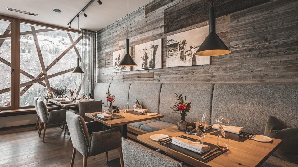 An elegant restaurant with wooden walls and cozy tables. The atmosphere is warm and inviting, with beautiful decorations on the tables.