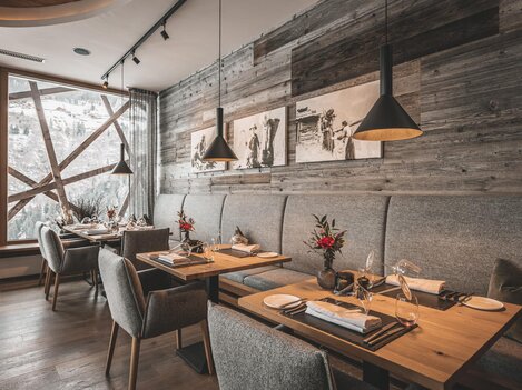 An elegant restaurant with wooden walls and cozy tables. The atmosphere is warm and inviting, with beautiful decorations on the tables.