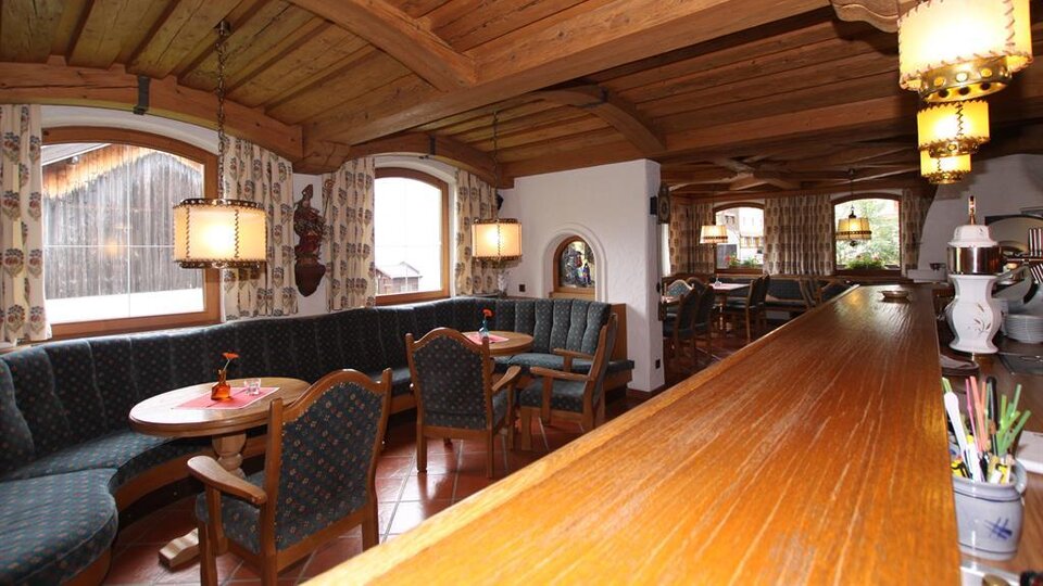 A cozy restaurant with wooden furniture and an inviting atmosphere.  
The windows offer a view of the surroundings, and the pleasant lighting creates a warm ambiance.