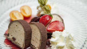 A delicious dessert plate with chocolatey chocolate ice cream, strawberries, and kiwis. Cream and fresh mint complete the arrangement.