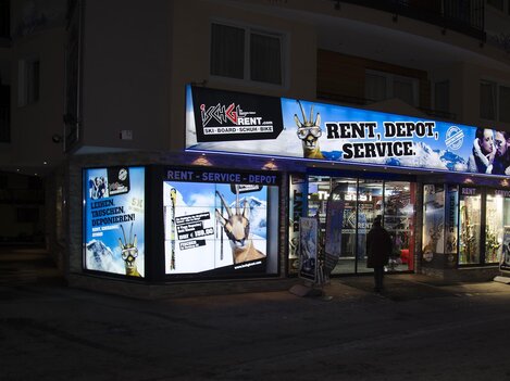 A business with a illuminated facade that offers services such as rental and storage. The advertising is eye-catching and informs about the services offered.