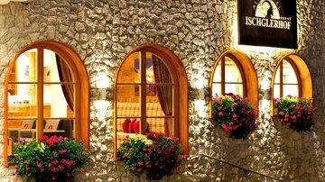 A cozy hotel with a rocky facade and large, curved windows. Blooming flower boxes adorn the windows, giving the building an inviting charm.
