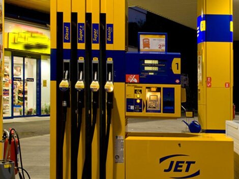 Eine Tankstelle mit mehreren Zapfsäulen und einem Kassenbereich. Es ist Abend, und die Umgebung ist gut beleuchtet.