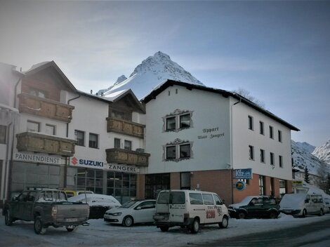 Ein charmantes Gebäude in den Bergen, umgeben von Schnee. Im Hintergrund ist ein majestätischer Gipfel zu sehen.