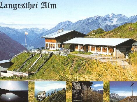 Eine malerische Alm umgeben von hohen Bergen und grünen Wiesen. Im Vordergrund ist das Gebäude der Langesthei Alm zu sehen.