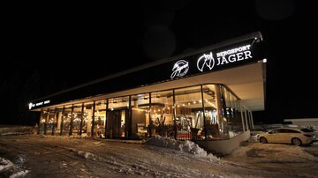 Ein modernes Geschäft für Sportartikel in einer verschneiten Umgebung bei Nacht. Das Gebäude hat große Fenster und eine einladende Beleuchtung.