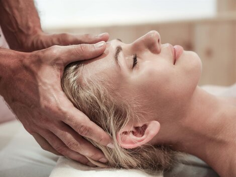 Eine Frau erhält eine entspannende Kopfmassage. Die Atmosphäre ist ruhig und beruhigend.
