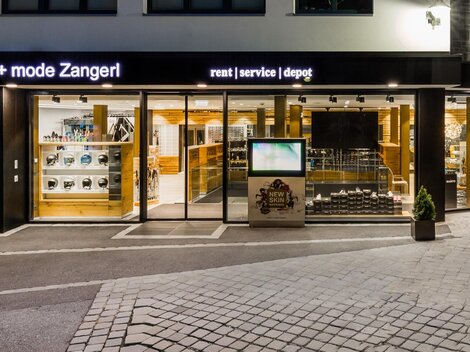 Ein Sportgeschäft mit großen Fenstern, das eine Vielzahl von Sportartikeln zeigt. Die Fassade ist modern und einladend, ideal für Sport- und Modebegeisterte.