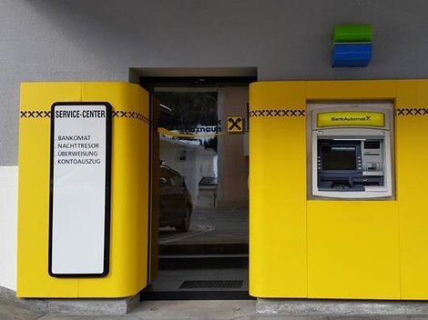 Ein Service-Center mit einem Geldautomaten in leuchtendem Gelb. Die Eingangstür ist sichtbar und der Bereich wirkt modern und einladend.
