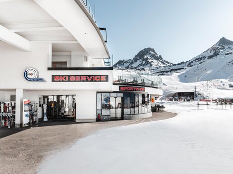 Ein moderner Ski-Service mit großen Fenstern und Ausblick auf schneebedeckte Berge. Die Umgebung ist von einer faszinierenden Winterlandschaft geprägt.