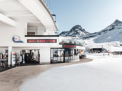 A modern ski service with large windows and a view of snow-covered mountains. The environment is characterized by a fascinating winter landscape.