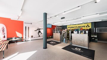 A modern sports store with ski and outdoor equipment. The walls are painted in vibrant colors, and there is a sales area with various brand products.