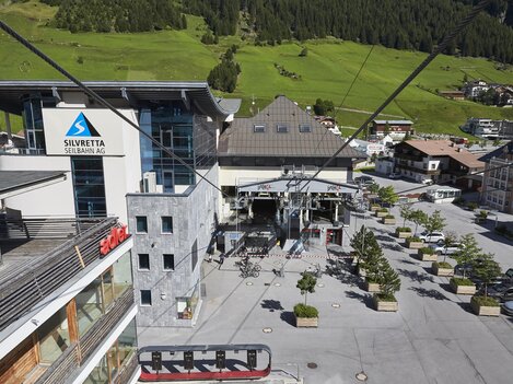 A modern lift area with a large building in the background. The surroundings are green and provide a cozy atmosphere.