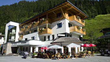 A cozy hotel with a modern and traditional design. There is a terrace with tables and chairs as well as a beautiful view of the surrounding mountains.
