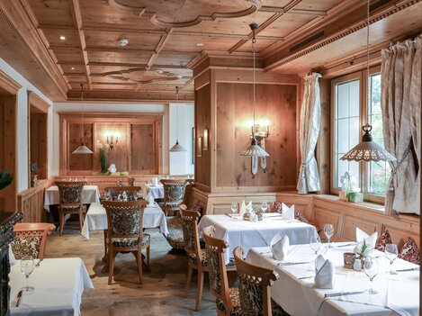 A cozy restaurant with wooden walls and elegantly set tables. Soft lighting creates an inviting atmosphere.