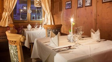 Ein gemütliches Restaurant mit Holzwänden und sanfter Beleuchtung. Die Tische sind elegant gedeckt und schaffen eine einladende Atmosphäre.