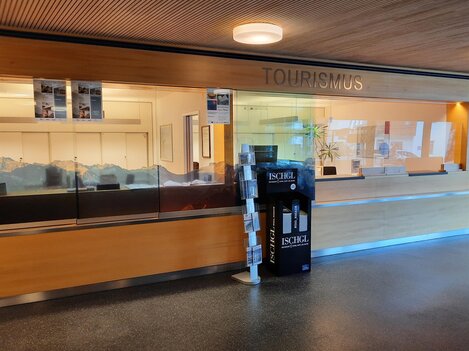 A reception area for tourism with a glass wall. On the floor, there is an information stand about the Ischgl region.