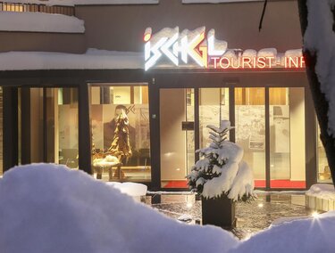 A modern building with the sign "Tourist Info" in a snowy landscape. The entrance is inviting and shows a wintry atmosphere.
