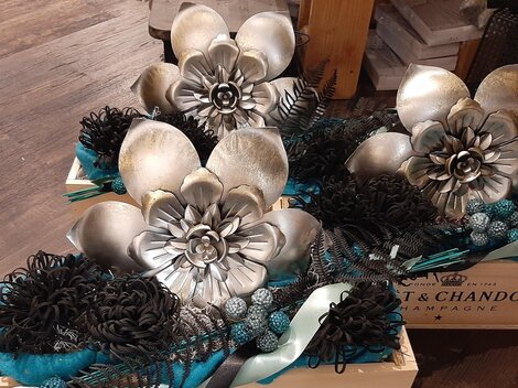 Zwei dekorative Kästen mit kunstvollen Blumenarrangements in Silber und Schwarz. Die Blumen sind in verschiedenen Formen angeordnet und verleihen einen eleganten Look.