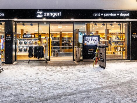Ein Geschäft mit Sport- und Freizeitkleidung. Der Eingangsbereich ist einladend und die Umgebung ist schneebedeckt.