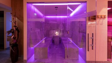 A modern spa with a glass entrance and atmospheric purple lighting. The interior feels relaxing and inviting.