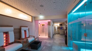 A modern wellness area with comfortable loungers and colored light. The room feels relaxing and inviting.