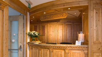 An inviting reception area with wooden paneling and a beautiful flower decoration. The reception is tidy and well-lit.