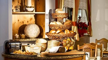 A lovingly set table with different types of bread and baskets. In the background, a cozy interior is visible.