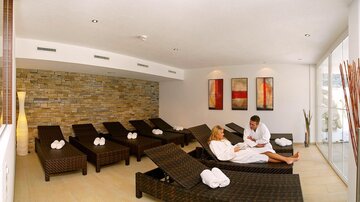 An elegant wellness area with loungers and soft lighting. Two people are relaxing in a laid-back atmosphere.