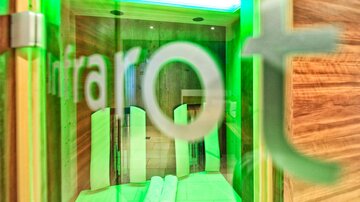 A modern infrared room with a relaxing atmosphere. The walls are made of wood and illuminated in green.