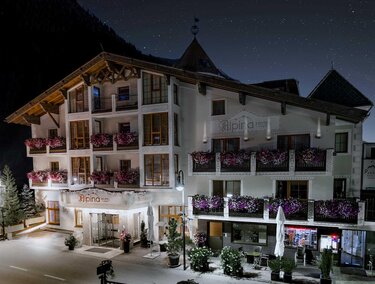Ein schönes Hotel mit blühenden Balkonpflanzen und einem einladenden Eingangsbereich. Die Umgebung ist ruhig und die Nacht hat einen klaren Sternenhimmel.