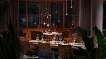 An elegant restaurant with stylishly set tables and soft lighting. The atmosphere is cozy and inviting.