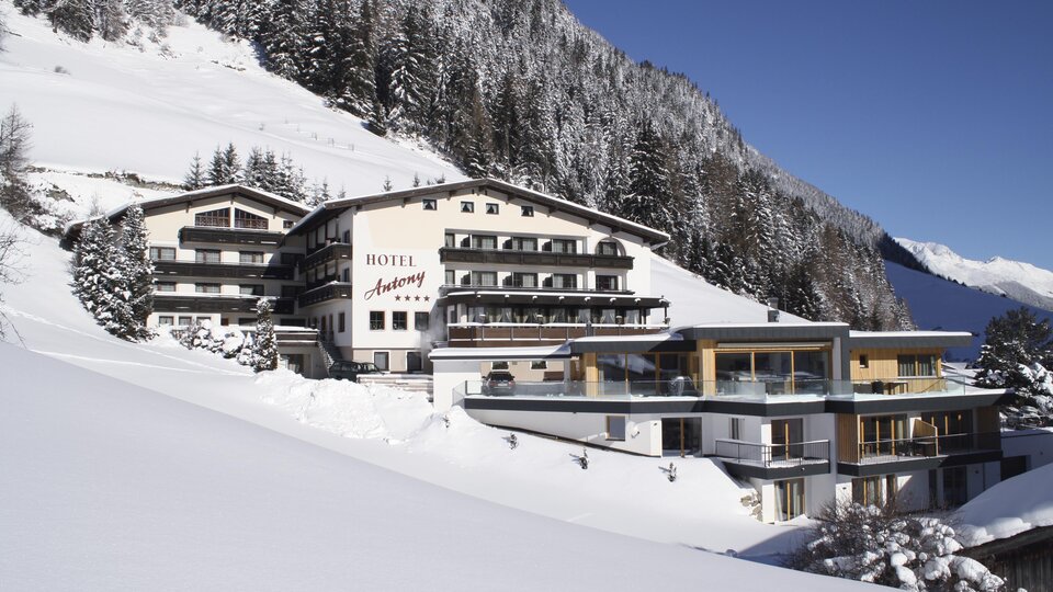 Ein luxuriöses Hotel in den Bergen, umgeben von schneebedeckten Landschaften. Die Architektur verbindet traditionelles Design mit modernen Elementen.