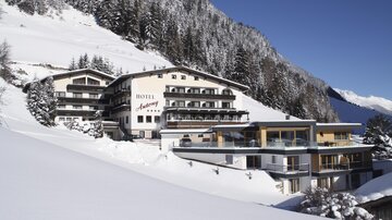 Ein luxuriöses Hotel in den Bergen, umgeben von schneebedeckten Landschaften. Die Architektur verbindet traditionelles Design mit modernen Elementen.