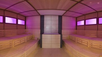 Eine moderne Sauna mit Holzbank und sanfter, pinker Beleuchtung. Der Raum ist gemütlich und einladend für Entspannung.