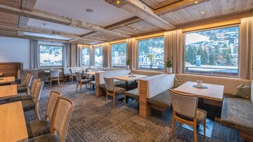 Ein gemütliches Restaurant mit Holzdekor und großen Fenstern. Die einladenden Tische bieten einen Blick auf die umliegende Landschaft.