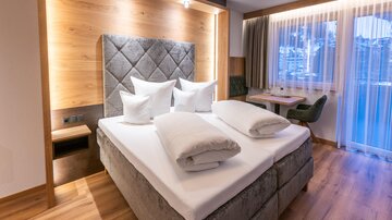 Ein modernes Schlafzimmer mit einem großen Bett und gemütlichen Kissen. Die warmen Holztöne schaffen eine einladende Atmosphäre.