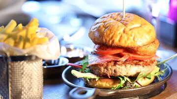 A juicy burger with tomatoes and lettuce in a crispy bun. It comes with a serving of french fries.