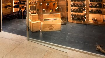 An elegant wine cellar with wood-paneled shelves full of wine bottles. The glass door offers a view of the carefully arranged collection.