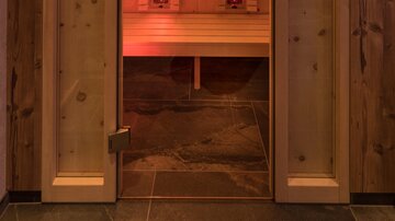 An infrared cabin with wooden paneling and orange lighting. The cabin is ready for use and conveys a warm, relaxing atmosphere.