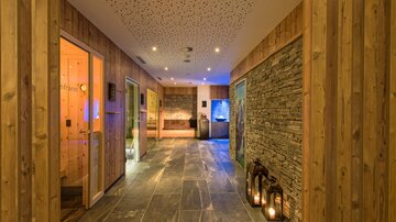 An elegant spa area with wooden paneling and stone walls. Soft light creates a relaxing atmosphere.